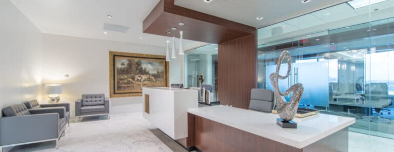 Contemporary office reception with white marble floors, modern furnishings, and a glass-walled meeting room by a commercial contractor in Orlando.